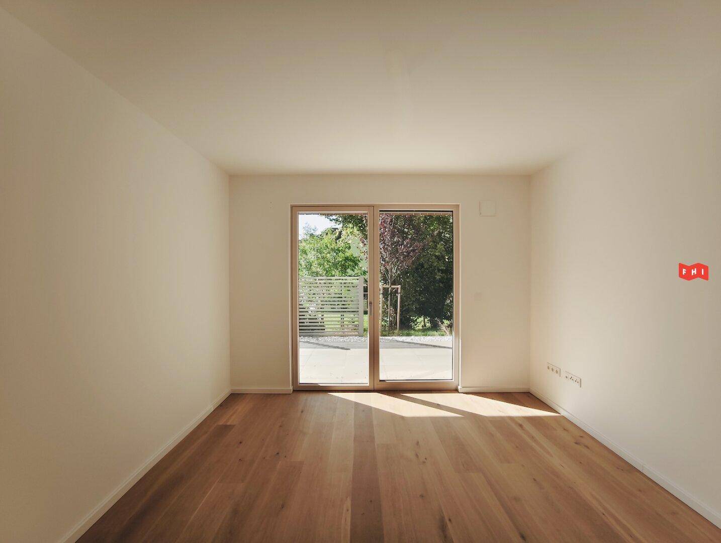 Helles Schlafzimmer mit Eichenparkett und Zugang zu einem Balkon oder einer Terrasse.