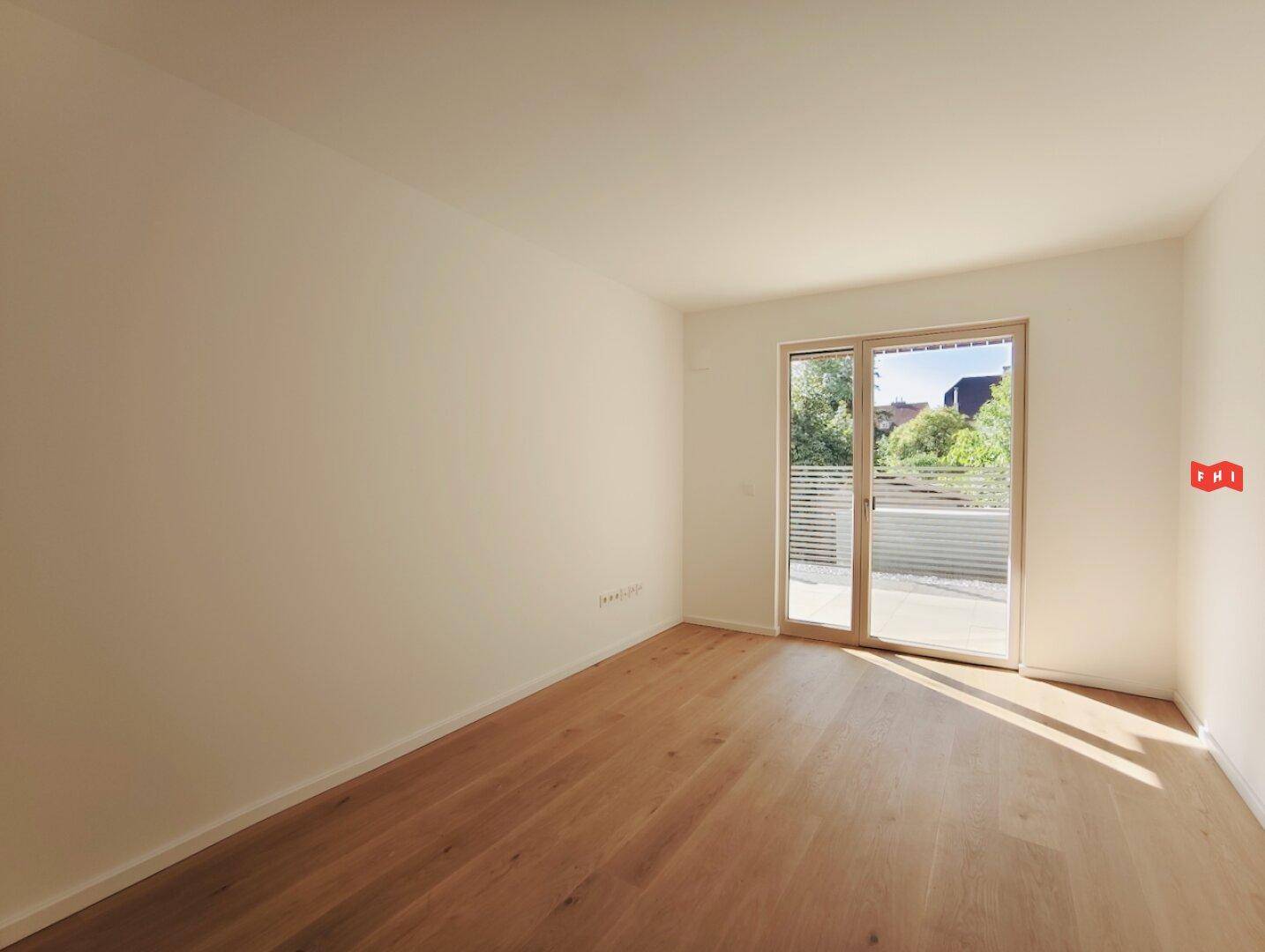 Geräumiges Schlafzimmer mit Eichenparkett und großen Fenstern, die viel Tageslicht bieten.