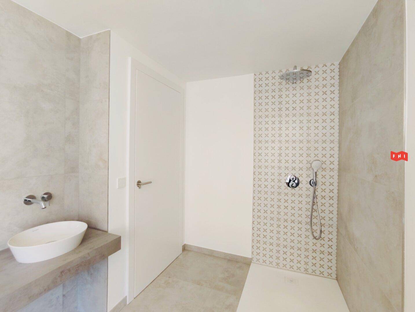 Modernes Badezimmer mit ebenerdiger Dusche, stilvollen Fliesen und Einzelwaschbecken.