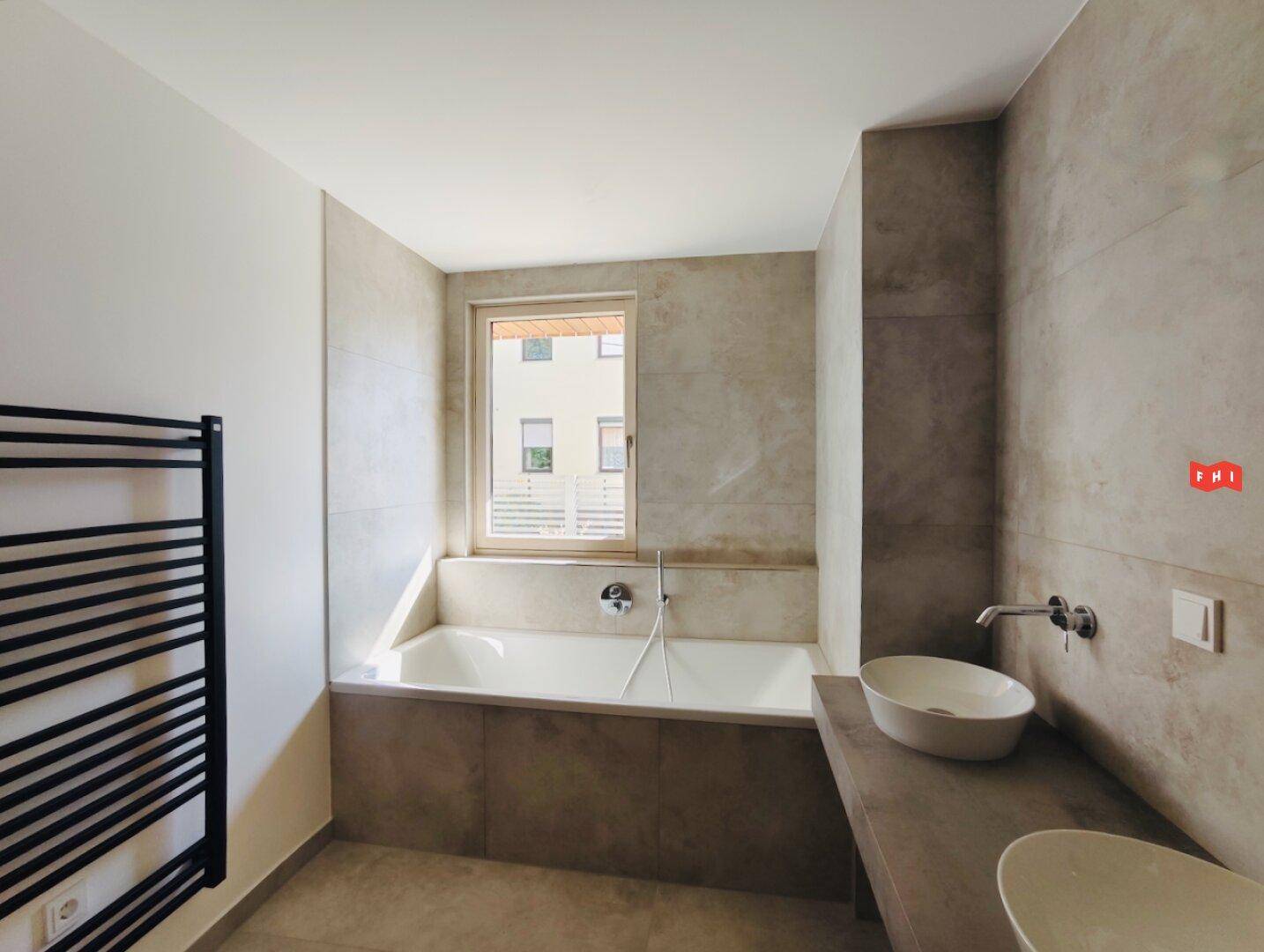 Modernes Badezimmer mit Badewanne, Doppelwaschbecken und beheiztem Handtuchhalter.