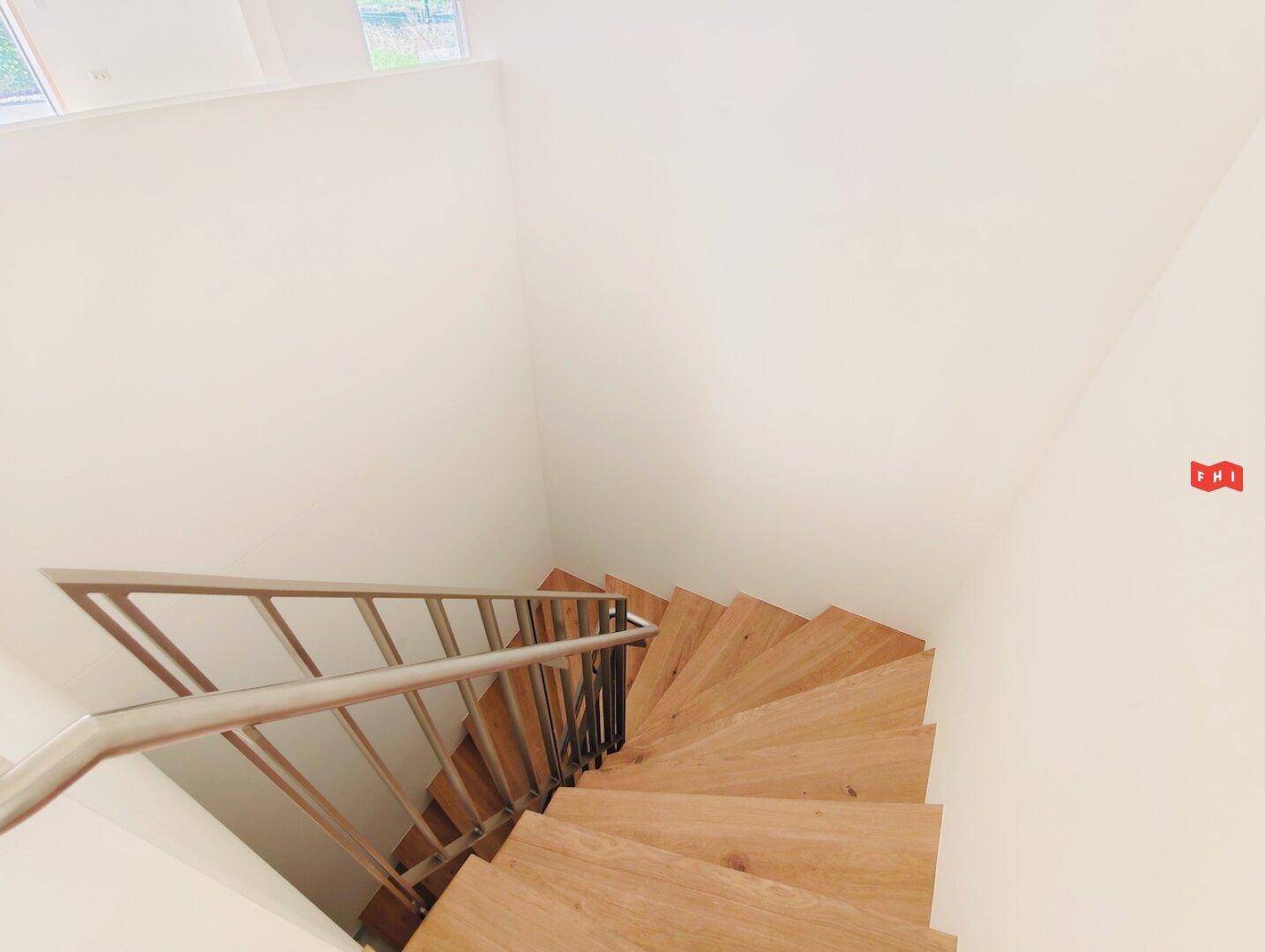 Moderne Holztreppe mit Metallgeländer, die die verschiedenen Ebenen des Hauses verbindet.