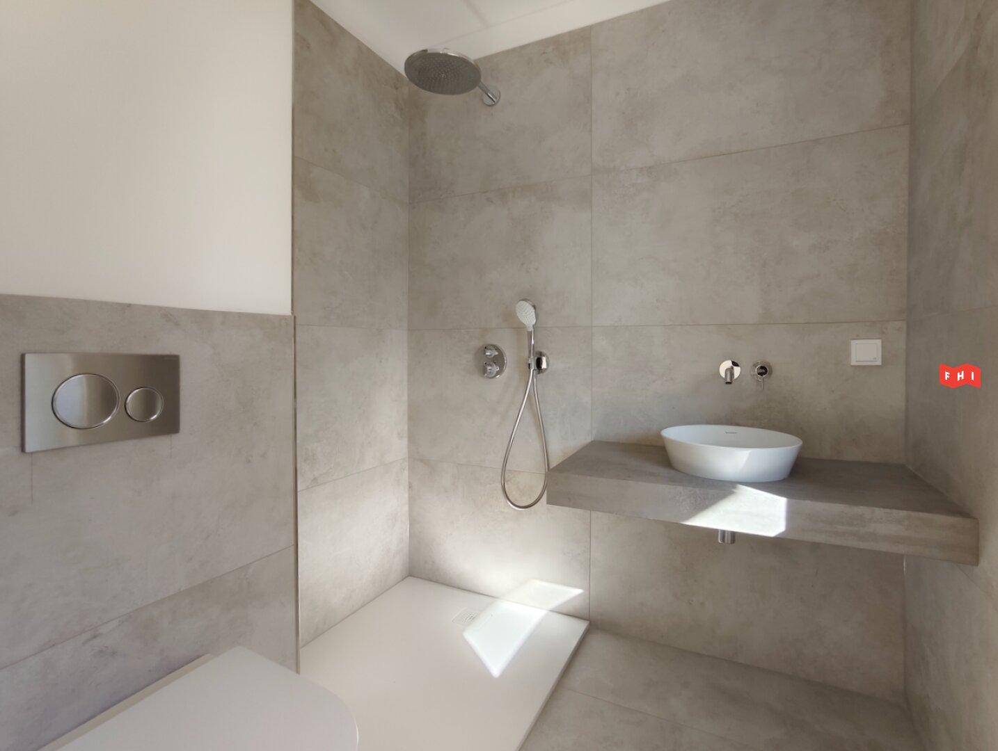 Modernes Badezimmer mit ebenerdiger Dusche, Wand-WC und stilvollem Einzelwaschbecken.