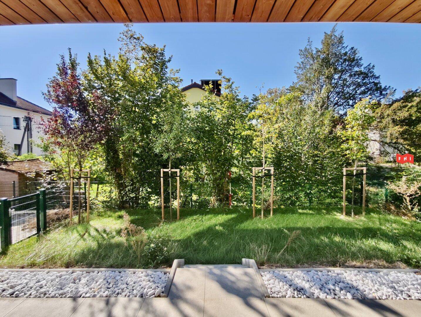 Gepflegter Gartenbereich mit jungen Bäumen und einer kleinen Treppe zur Terrasse.