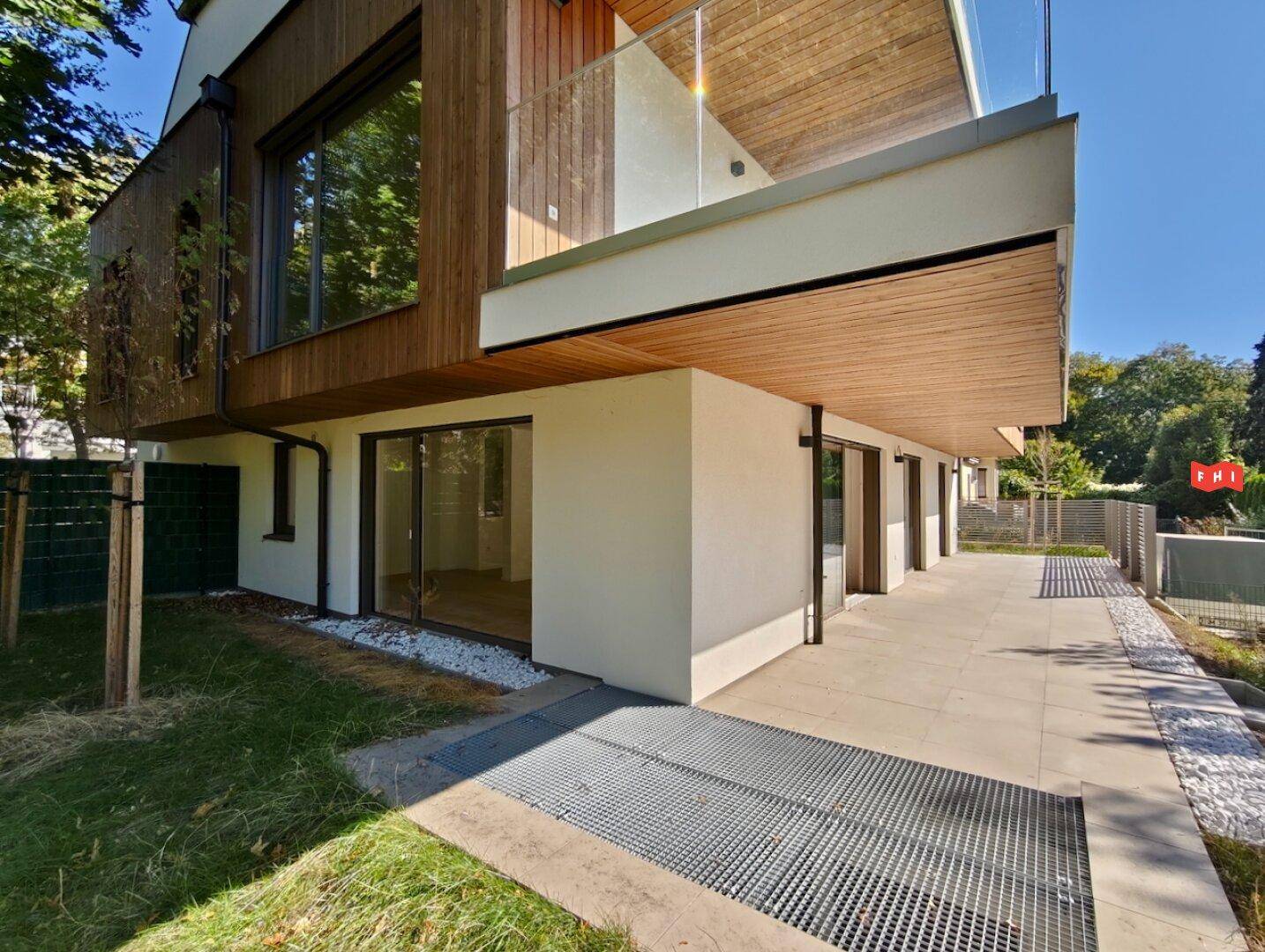 Seitenansicht des modernen Gebäudes mit Terrasse und Zugang zum Gartenbereich.