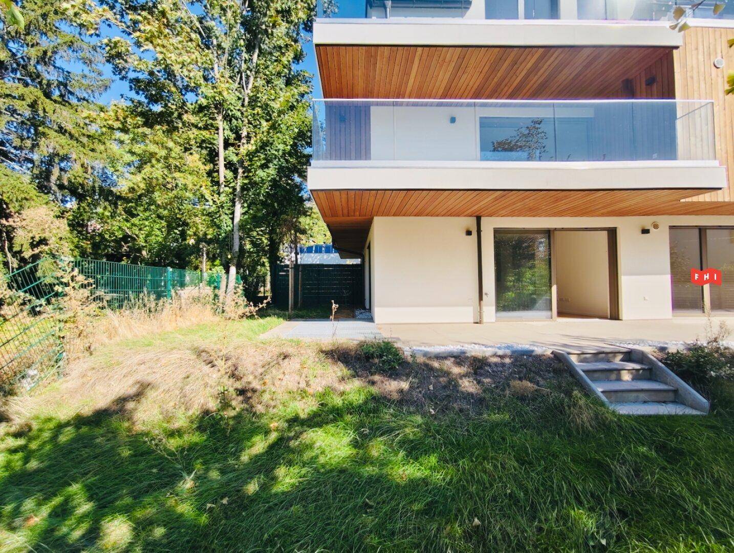Grünfläche mit leichter Hanglage und direktem Zugang zur Terrasse eines modernen Wohnhauses.