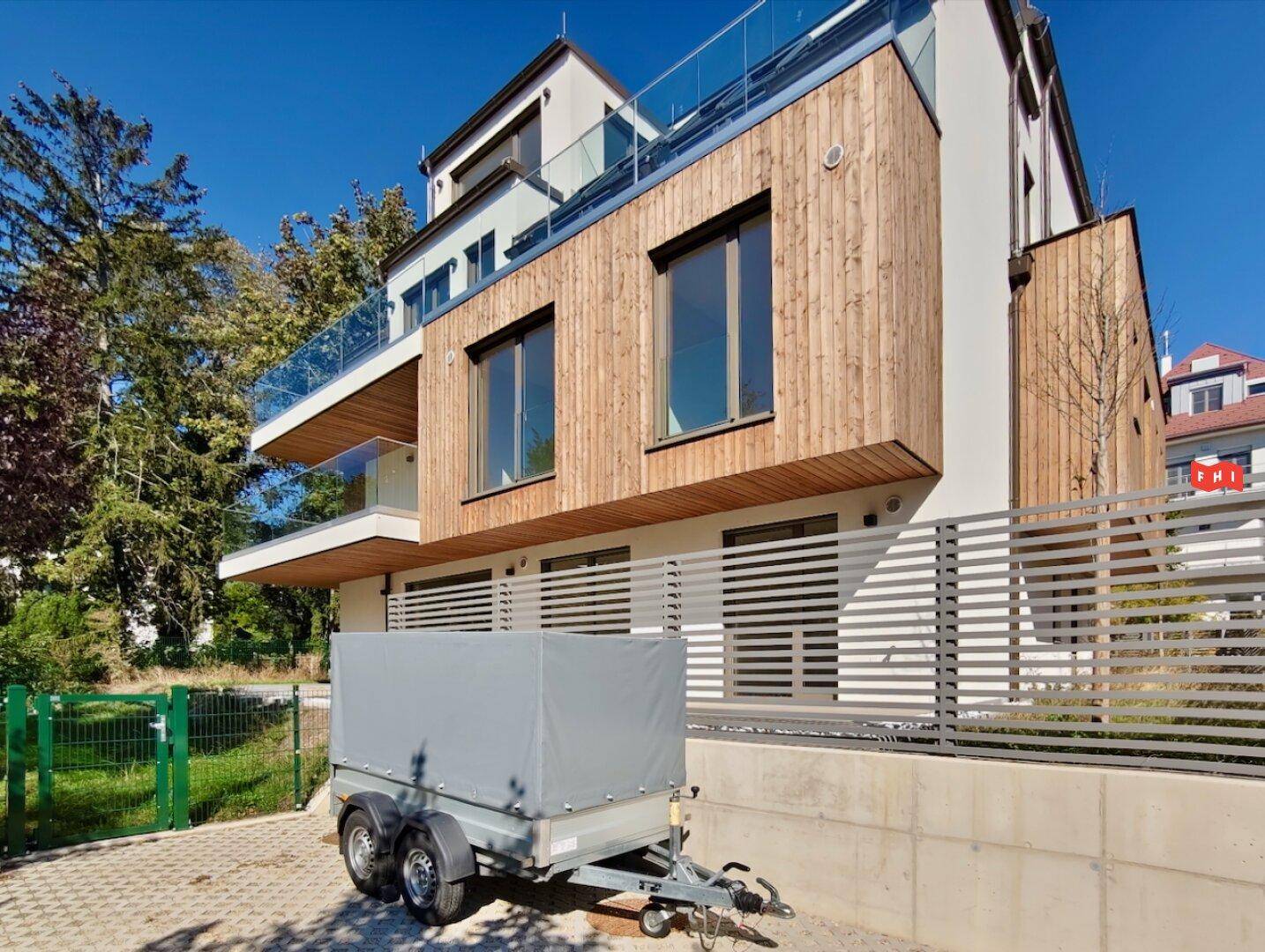 Seitenansicht des modernen Gebäudes mit mehreren Balkonen und Holzverkleidung, bei strahlendem Sonnenschein.