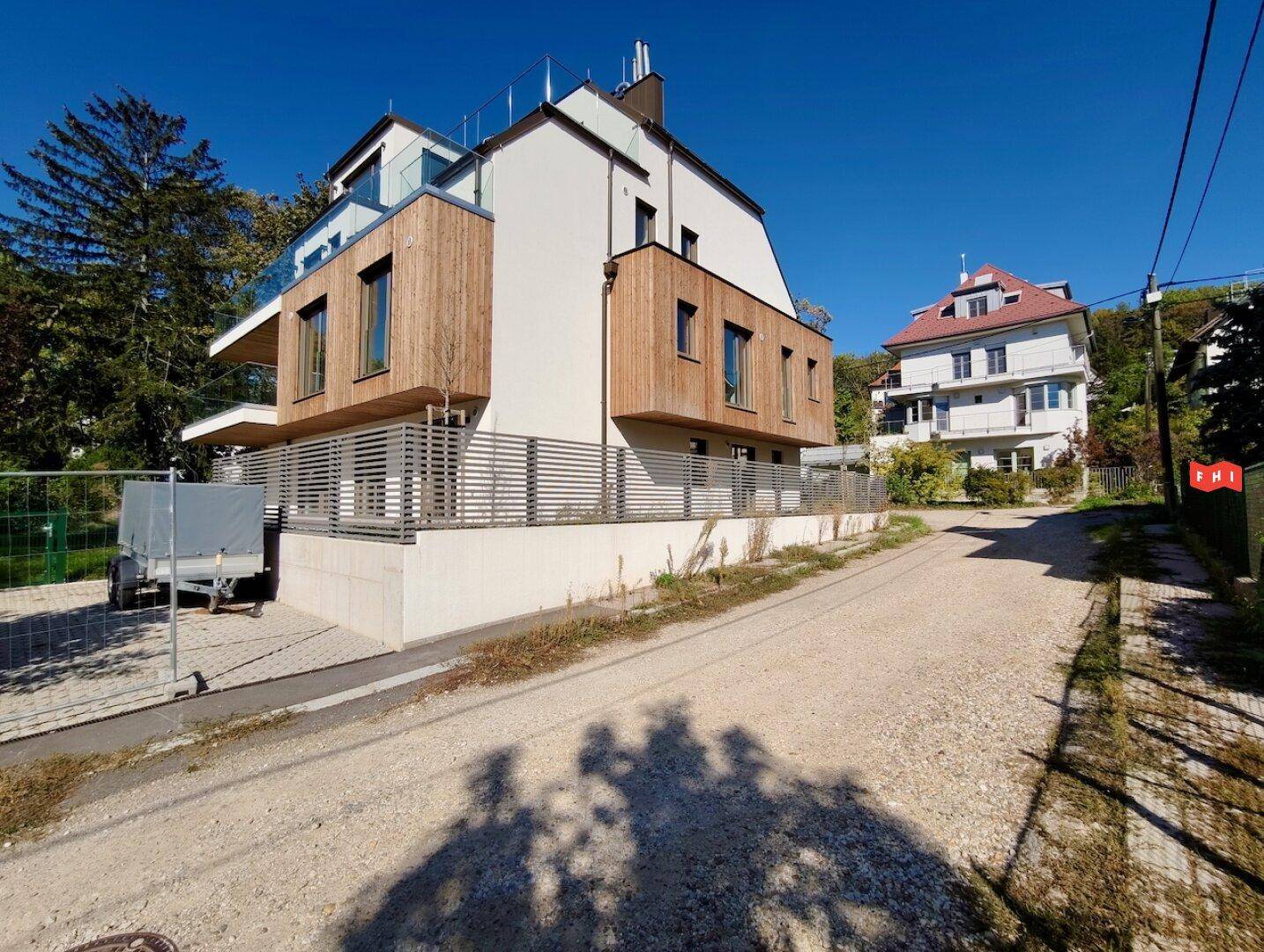 Das moderne Gebäude von unten gesehen, mit Kiesweg und einem weiteren Haus in der Ferne.