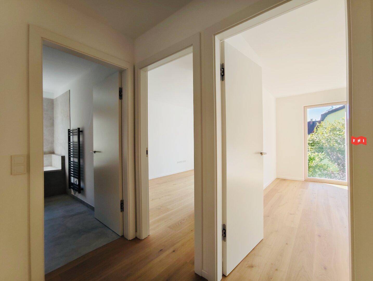 Flur mit Zugang zu einem Badezimmer und einem weiteren Zimmer, ausgestattet mit Parkettboden.