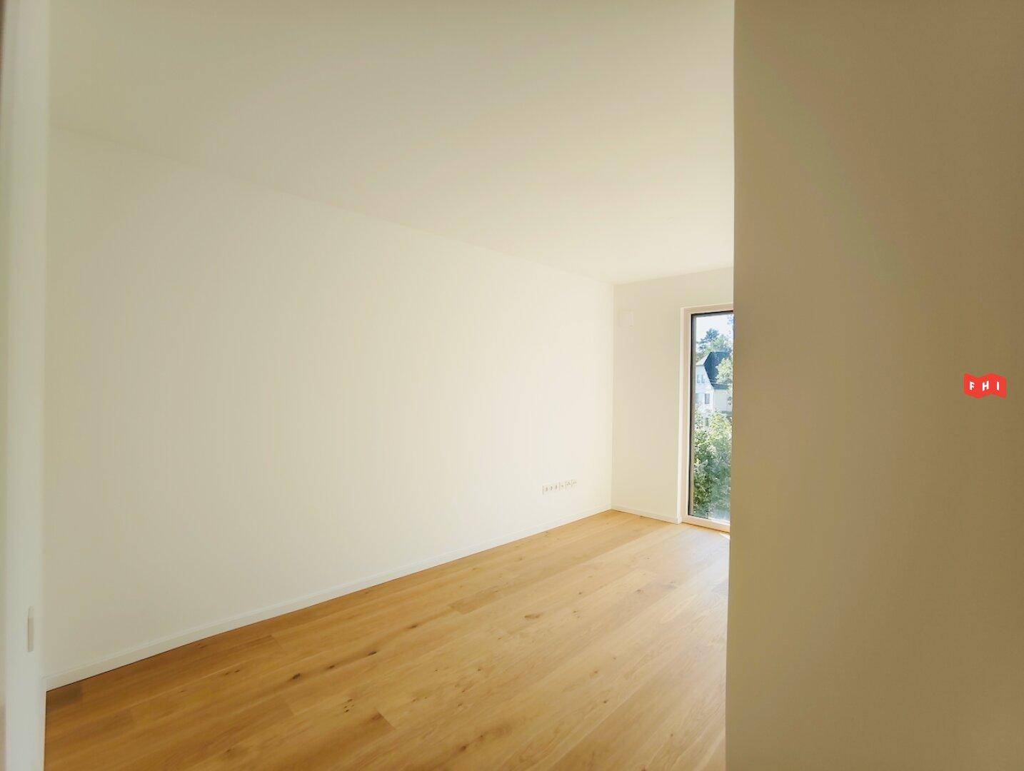 Leeres Zimmer mit hellem Parkettboden und weiß gestrichenen Wänden, bereit zur Einrichtung.