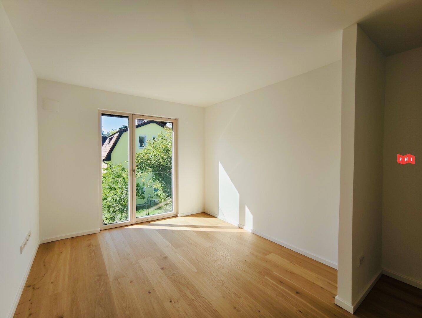 Sonniges Zimmer mit Eichenparkett und großem Fenster, das eine angenehme Atmosphäre schafft.