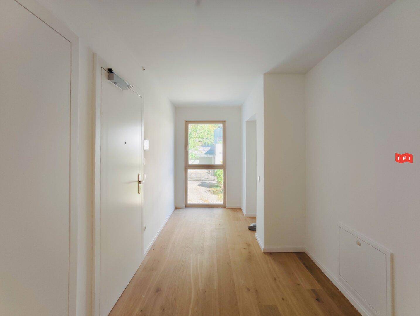 Heller Eingangsbereich mit Holzboden und viel Tageslicht durch die Eingangstür.