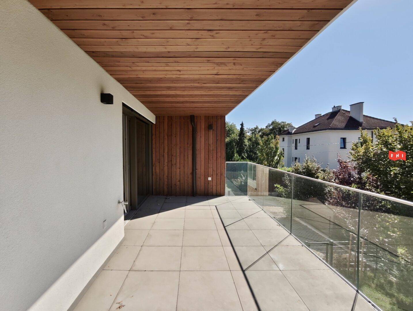 Moderner Balkon mit Glasgeländer und Holzverkleidung, ideal für entspannte Stunden im Freien.