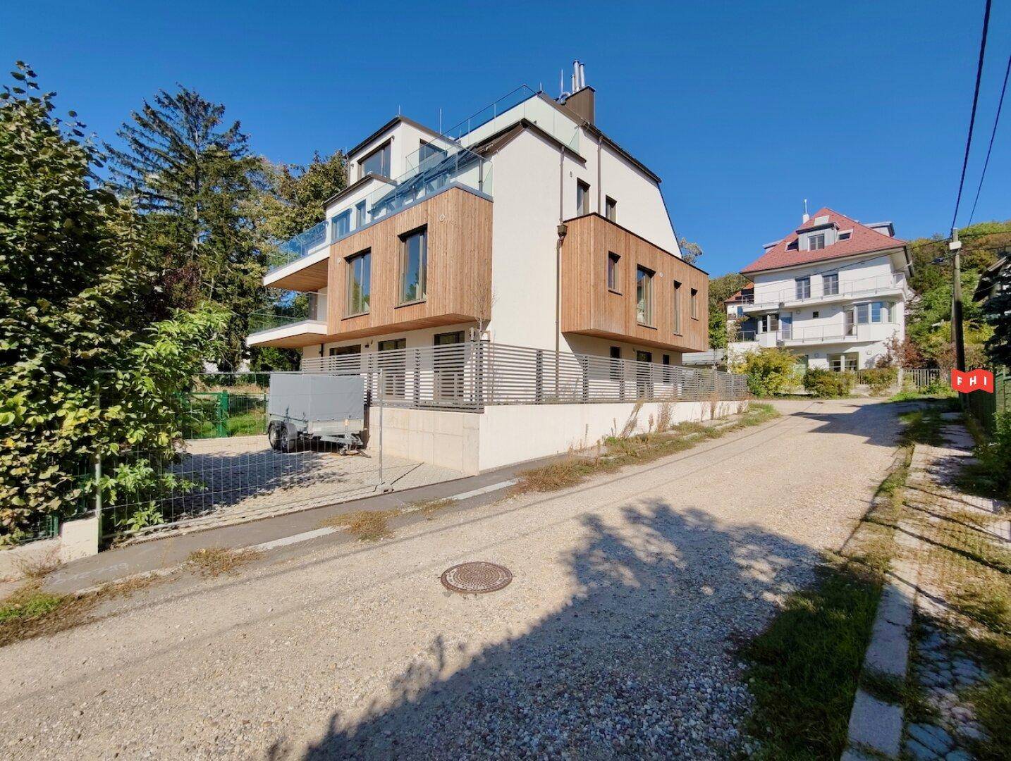 Moderne Wohnanlage mit Glasbalkonen, Holzfassadenelementen und einem Anhänger im Vordergrund.