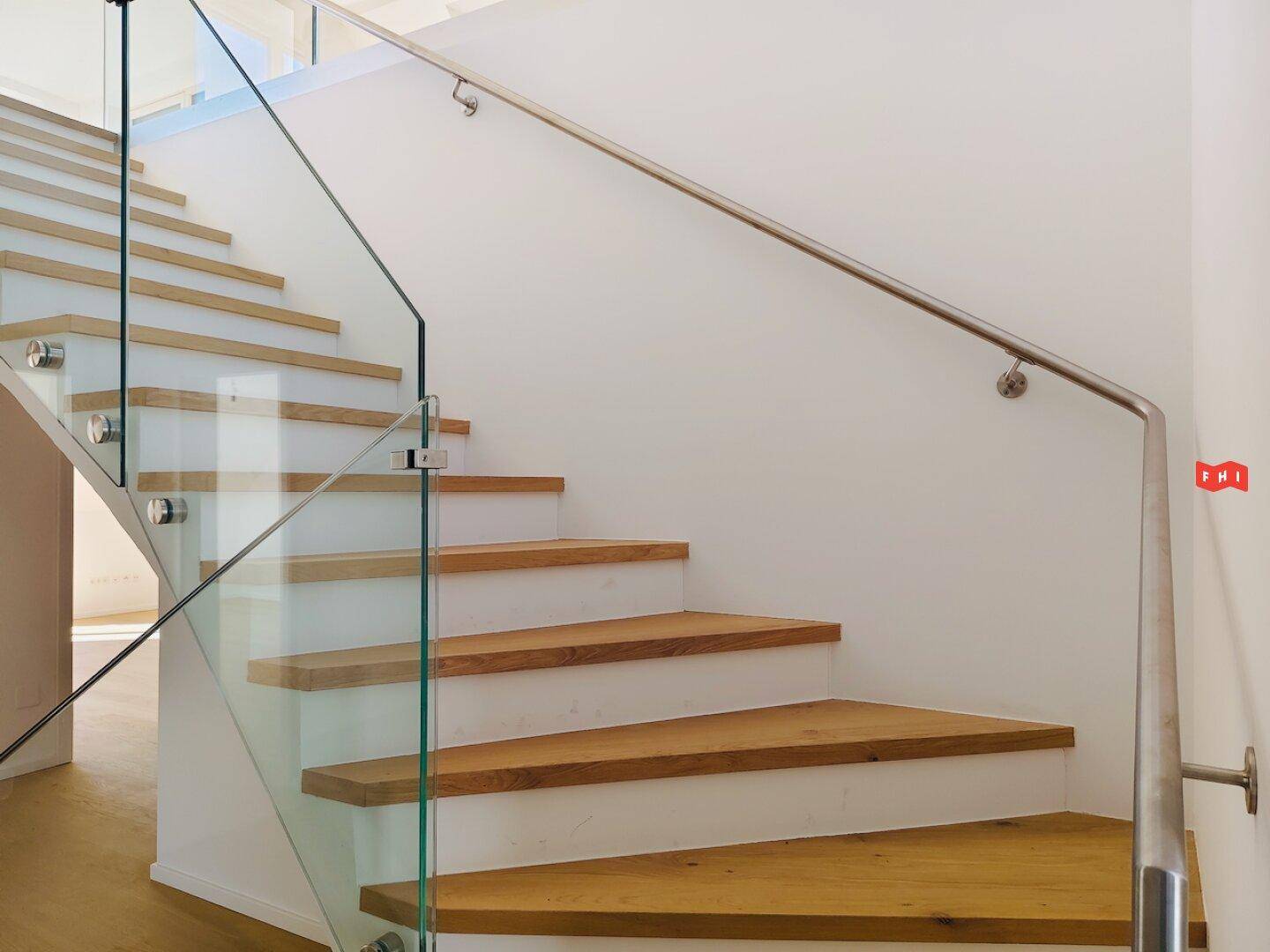 Detailansicht einer modernen Holztreppe mit elegantem Glasgeländer und Handlauf.