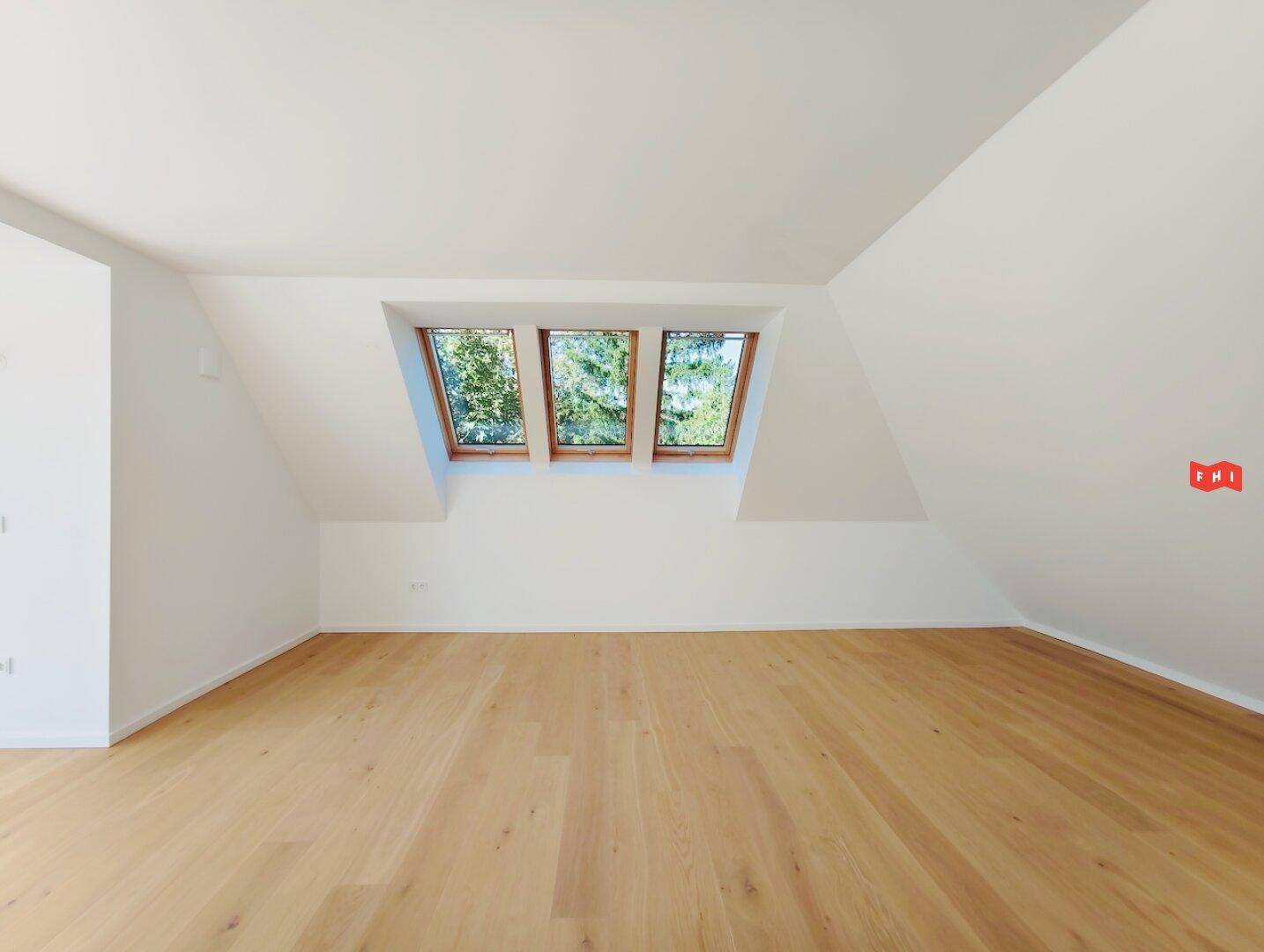 Helles Zimmer im Dachgeschoss mit Holzboden, Dachfenstern und viel Tageslicht.