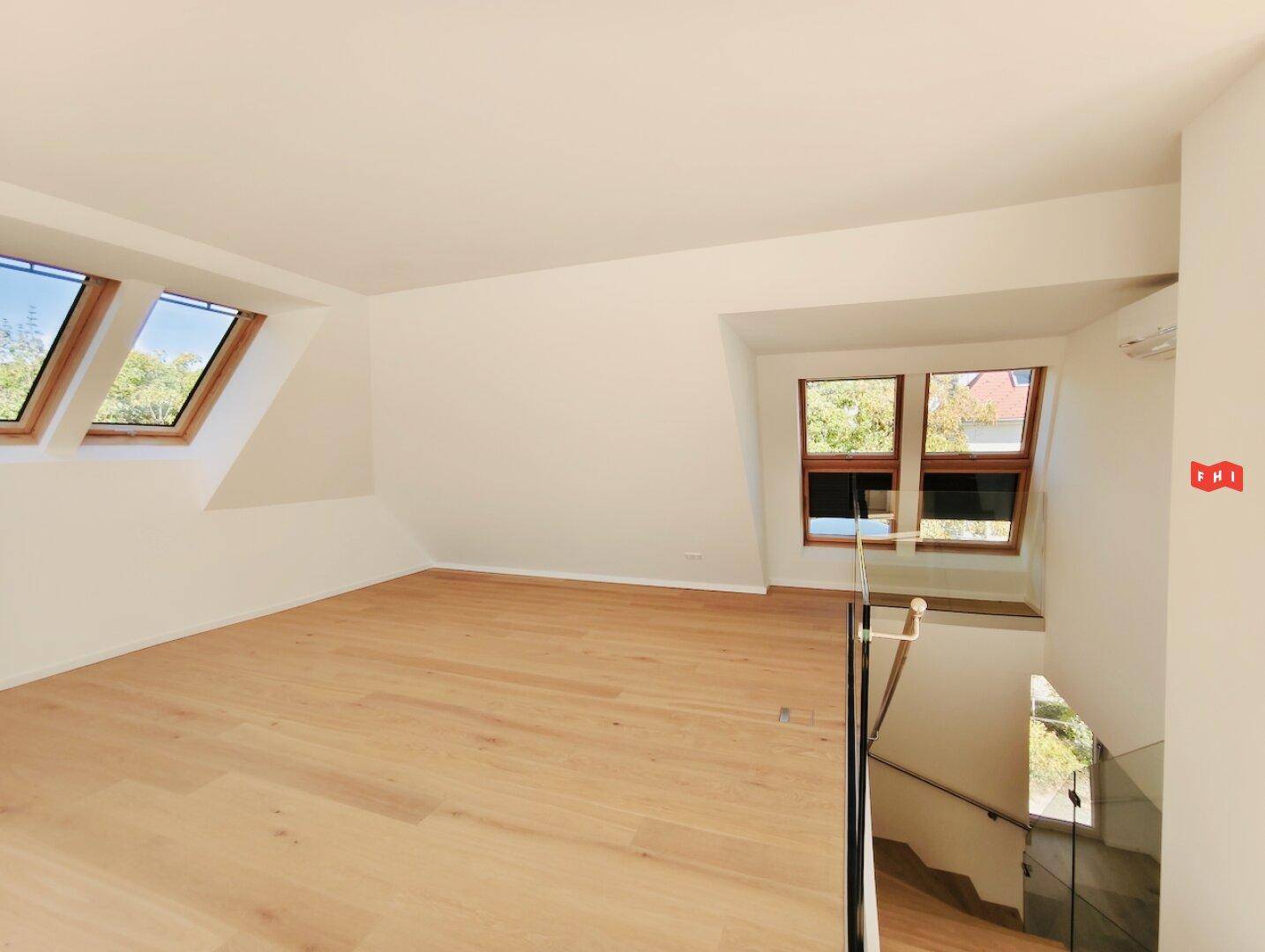Geräumiges Zimmer im Dachgeschoss mit Holzboden, Dachfenstern und Blick ins Grüne.
