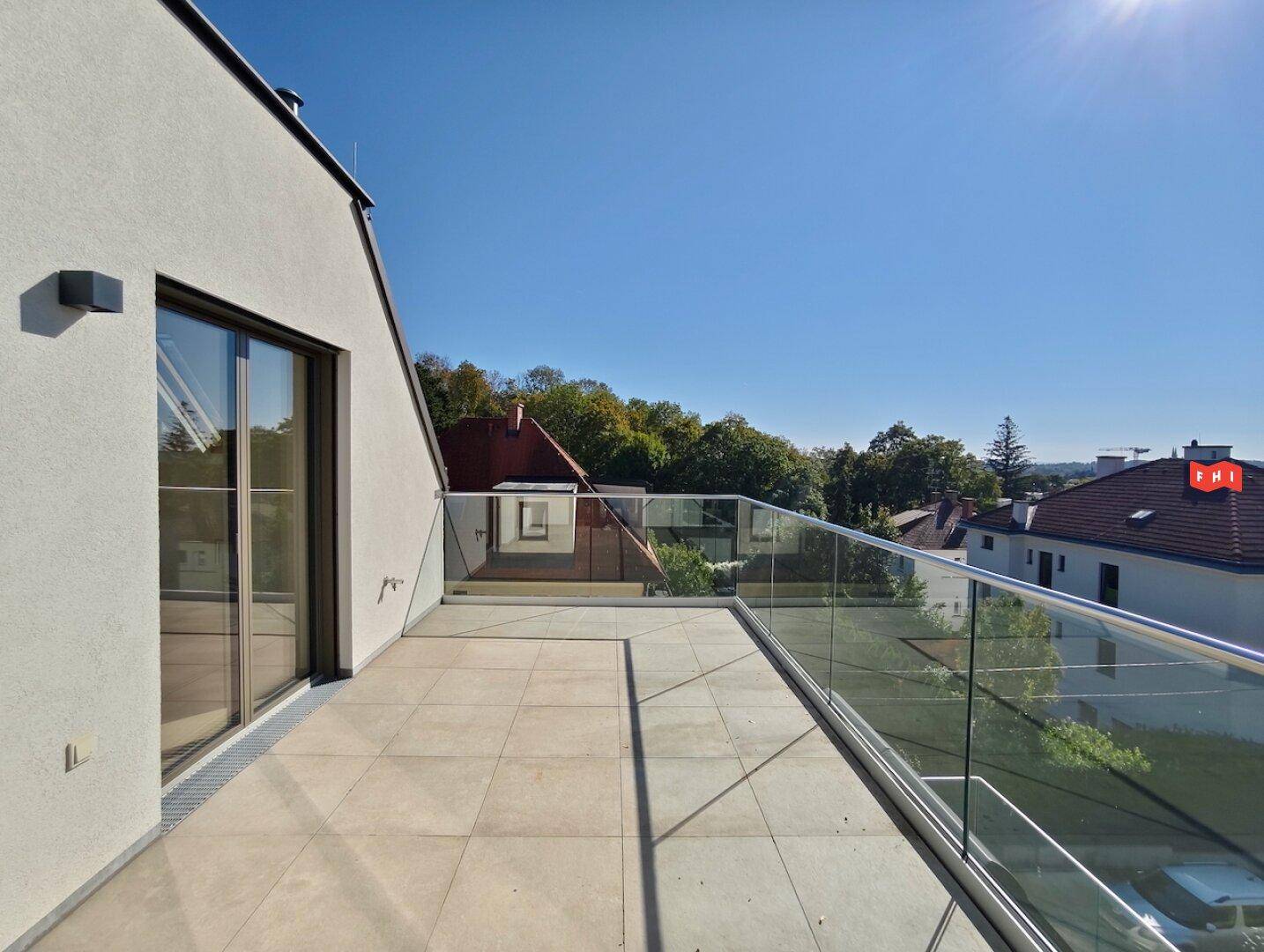 Sonniger Balkon mit Glasgeländer und weitem Blick über die umliegende Wohngegend.