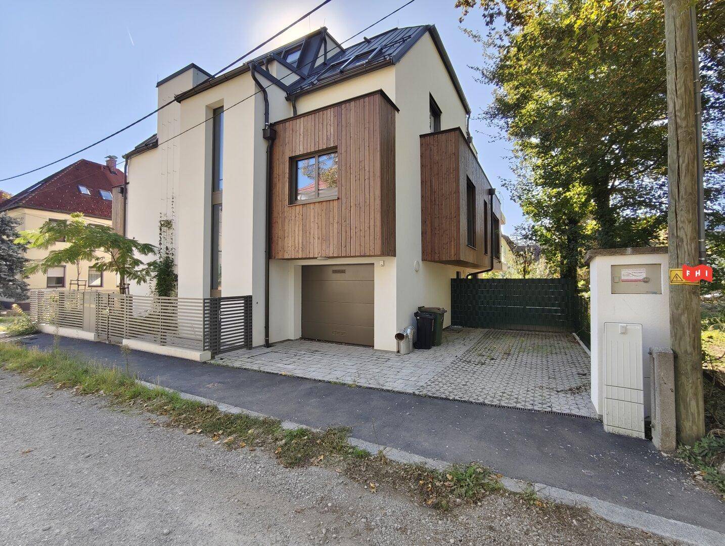 Modernes Wohnhaus mit integrierter Garage, gepflasterter Einfahrt und Holzfassadenelementen.