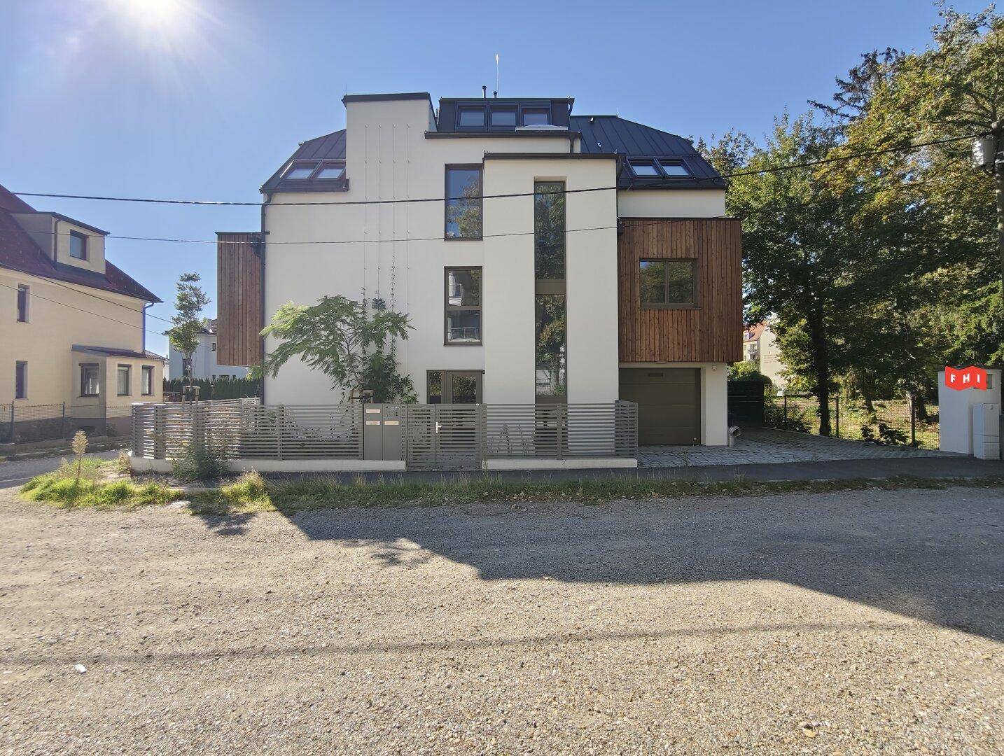 Attraktives Mehrfamilienhaus mit moderner Architektur, weißer Fassade und Holzakzenten in sonniger Lage.