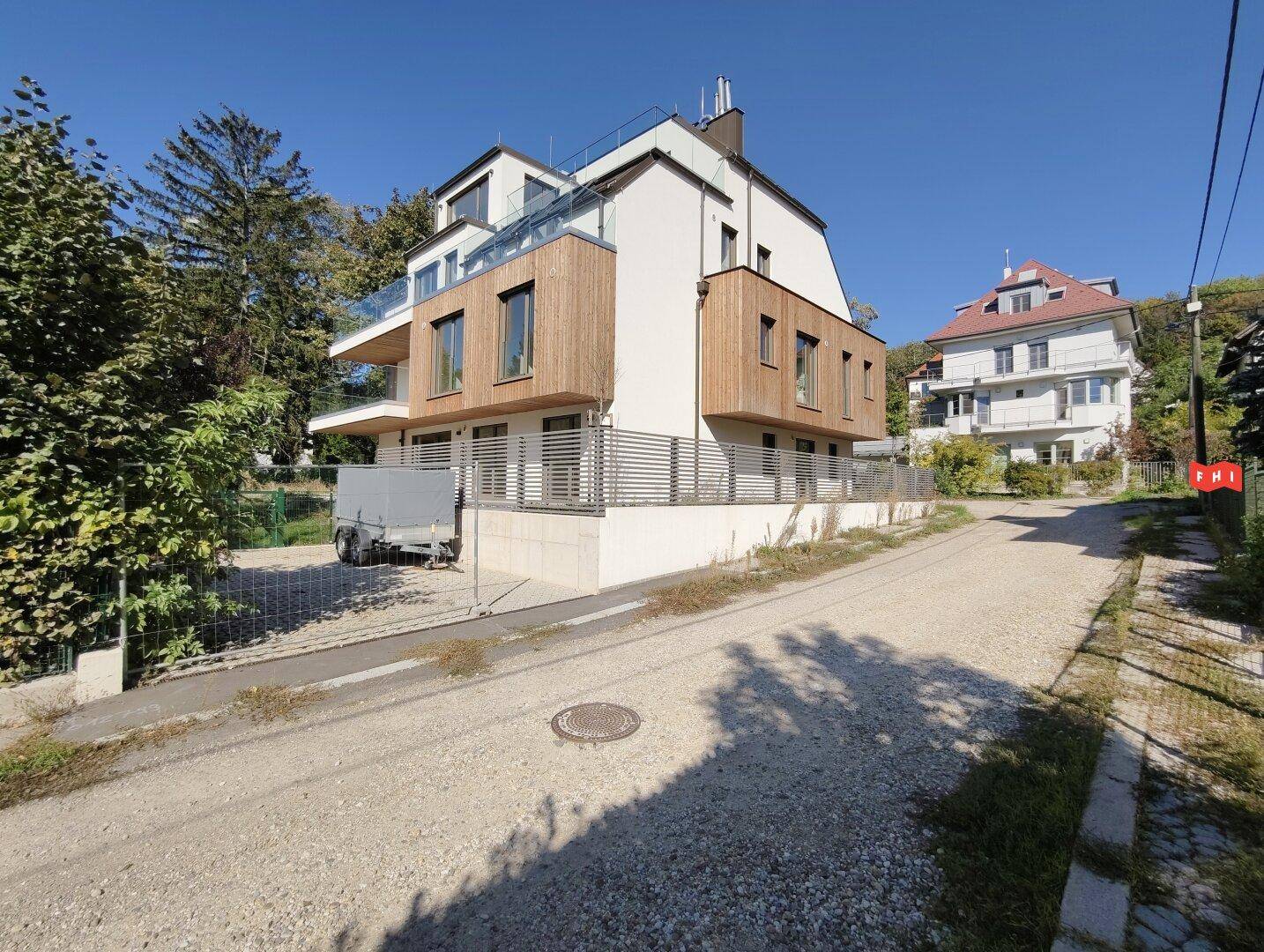Modernes Wohngebäude mit mehreren Balkonen und Holzfassadenelementen in einer ruhigen Wohngegend.