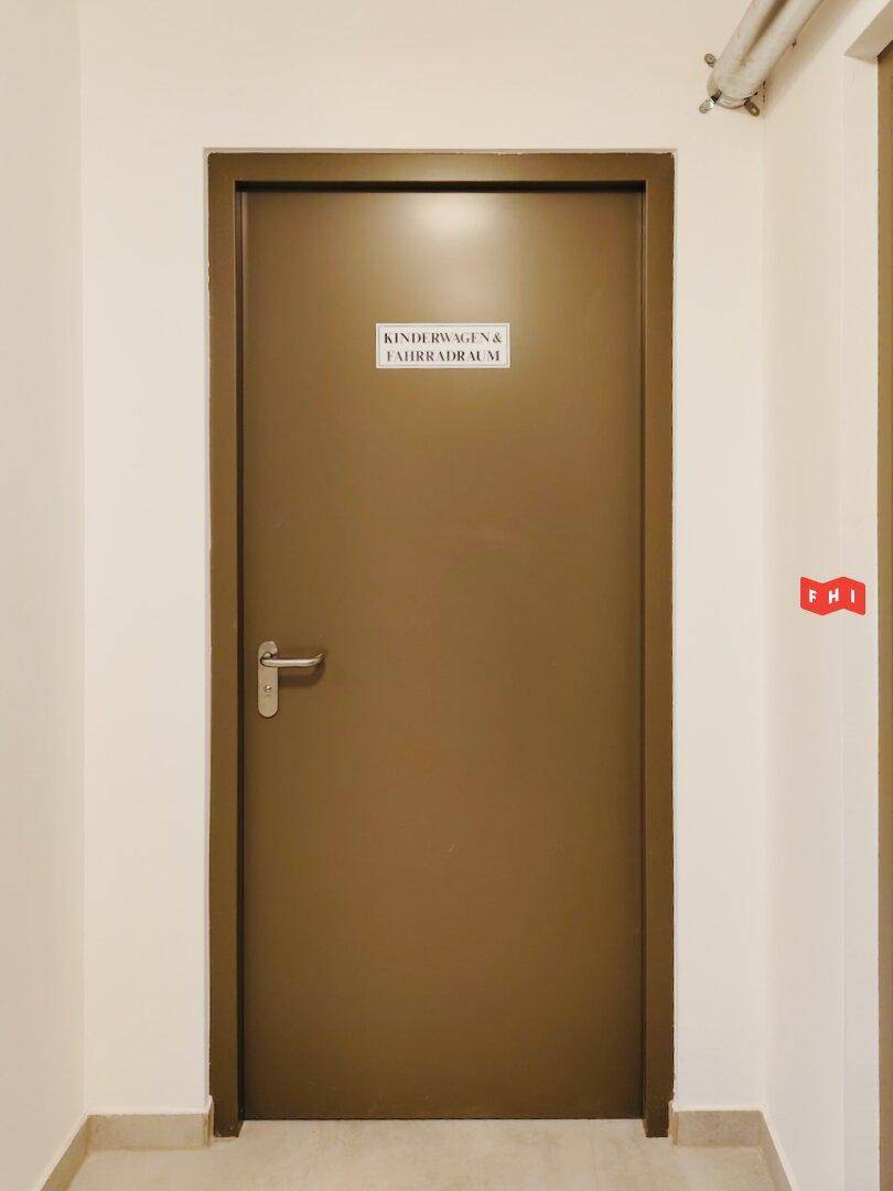 Tür zu einem Gemeinschaftsraum für Kinderwagen und Fahrräder, der praktischen Stauraum bietet.