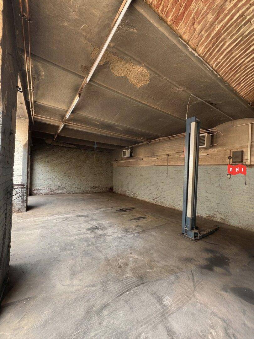 Geräumige, leere Garage oder Werkstatt mit einem Fahrzeuglift und Betonboden.