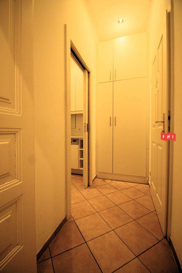 Flur mit Fliesenboden, Einbauschränken und Zugang zu einem weiteren Raum, möglicherweise einer Küche.