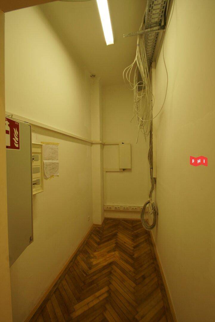 Schmaler Flur mit Fischgrätparkett und sichtbaren Kabeln, möglicherweise ein Technik- oder Abstellraum.