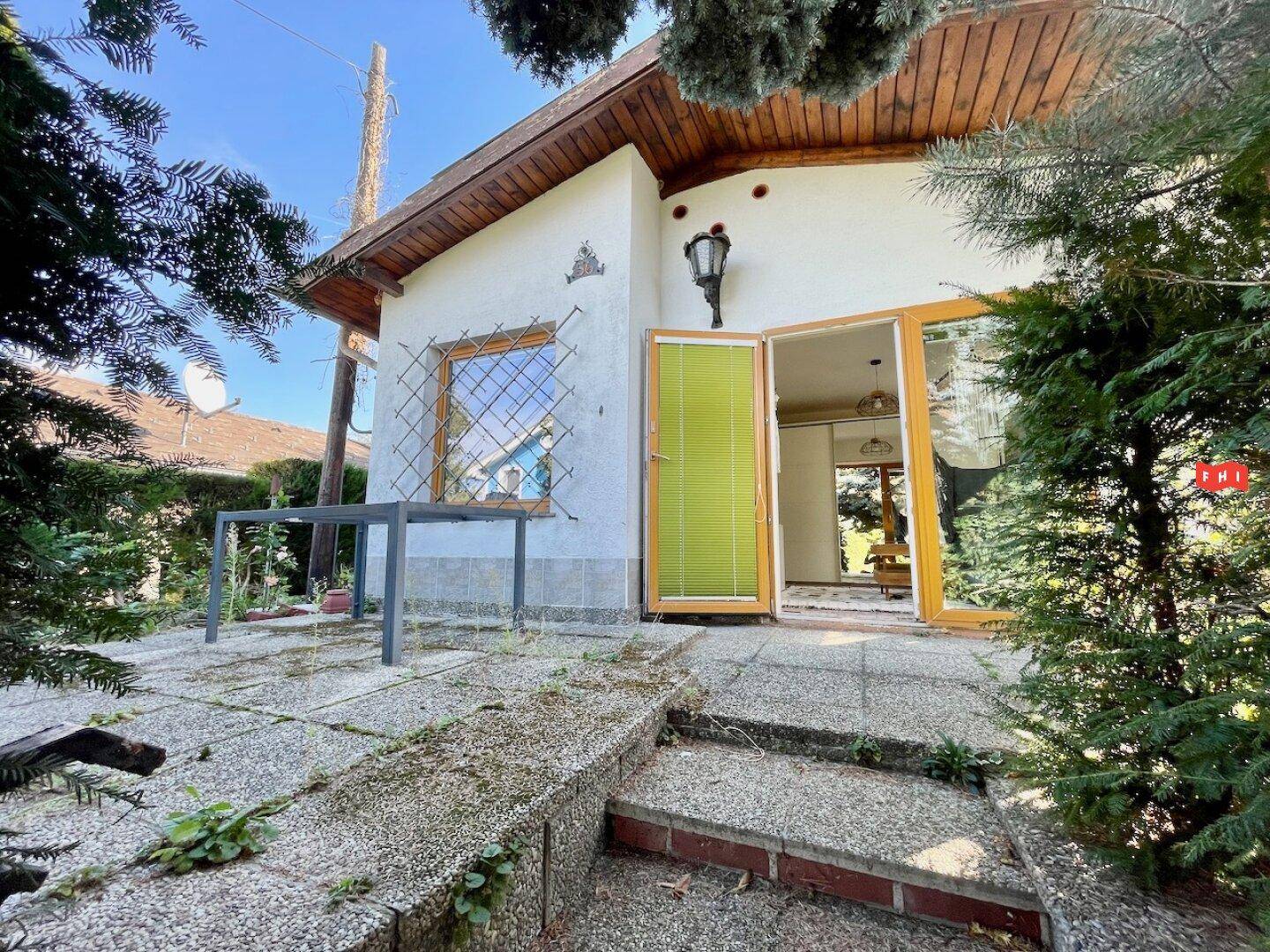 Gemütlicher Terrassenbereich vor dem Haus mit einem Tisch und Blick ins Grüne unter blauem Himmel.