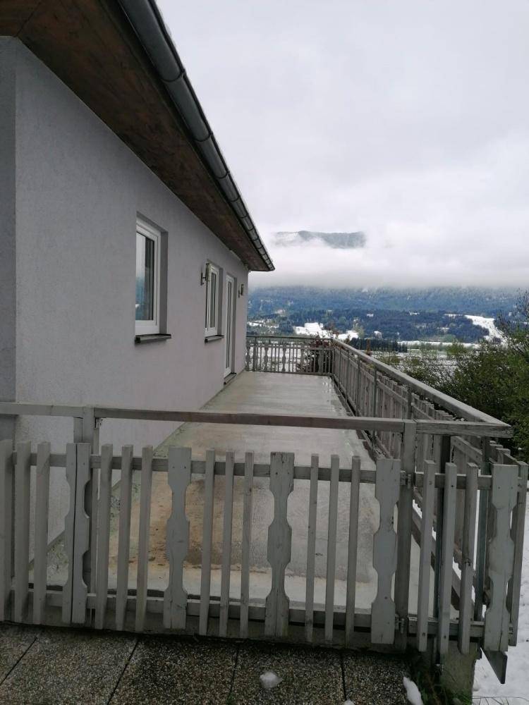 Balkon mit Holzbalkongeländer und weitem Blick über ein nebliges Tal im Winter.