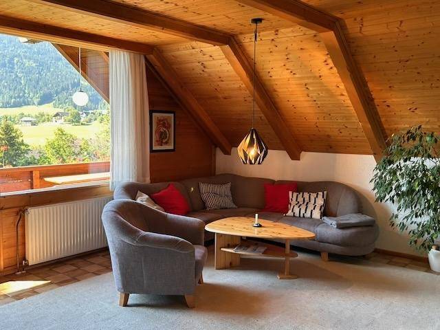Gemütliches Wohnzimmer im Dachgeschoss mit Holzbalken und Bergblick.