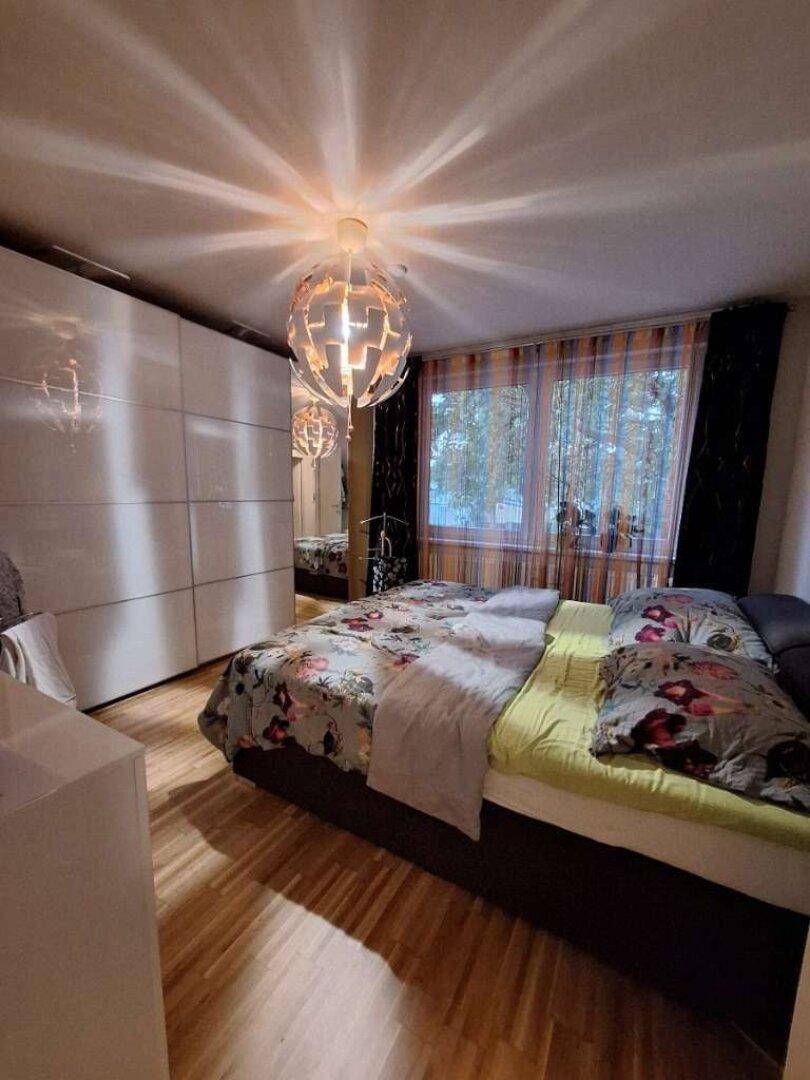 Gemütliches Schlafzimmer mit Holzboden, großem Bett und weißen Einbauschränken.