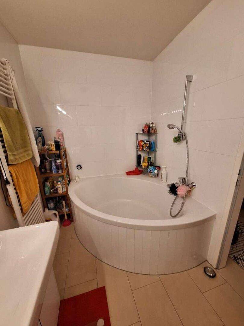 Badezimmer mit einer geräumigen Eckbadewanne und weißen Wandfliesen.