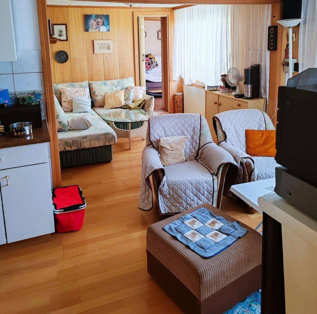 Wohnbereich mit Holzvertäfelung, bequemen Sitzmöbeln und Blick auf den Essbereich oder die Küche.