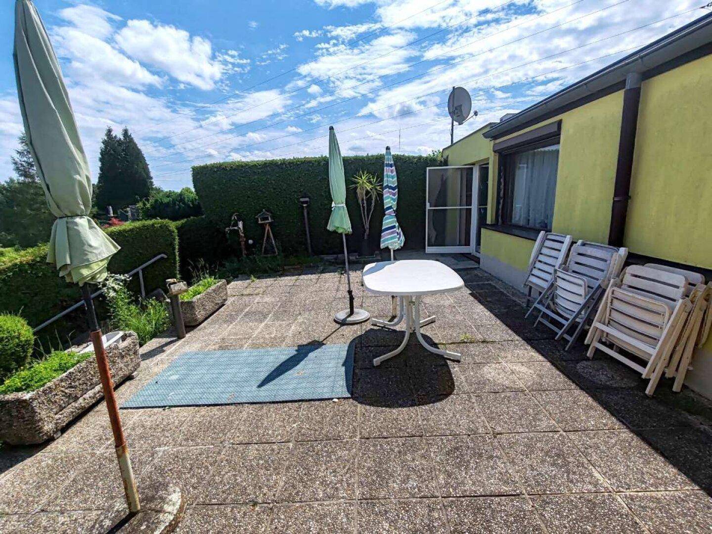 Geräumige Terrasse mit Sonnenschirmen und Gartenmöbeln, ideal für Entspannung im Freien.