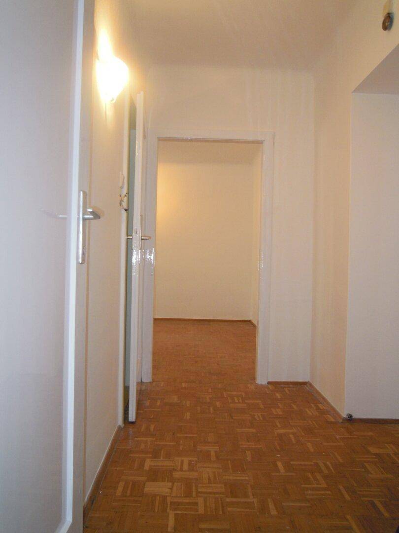 Heller Flur mit Parkettboden und Zugang zu mehreren Zimmern, gut beleuchtet.
