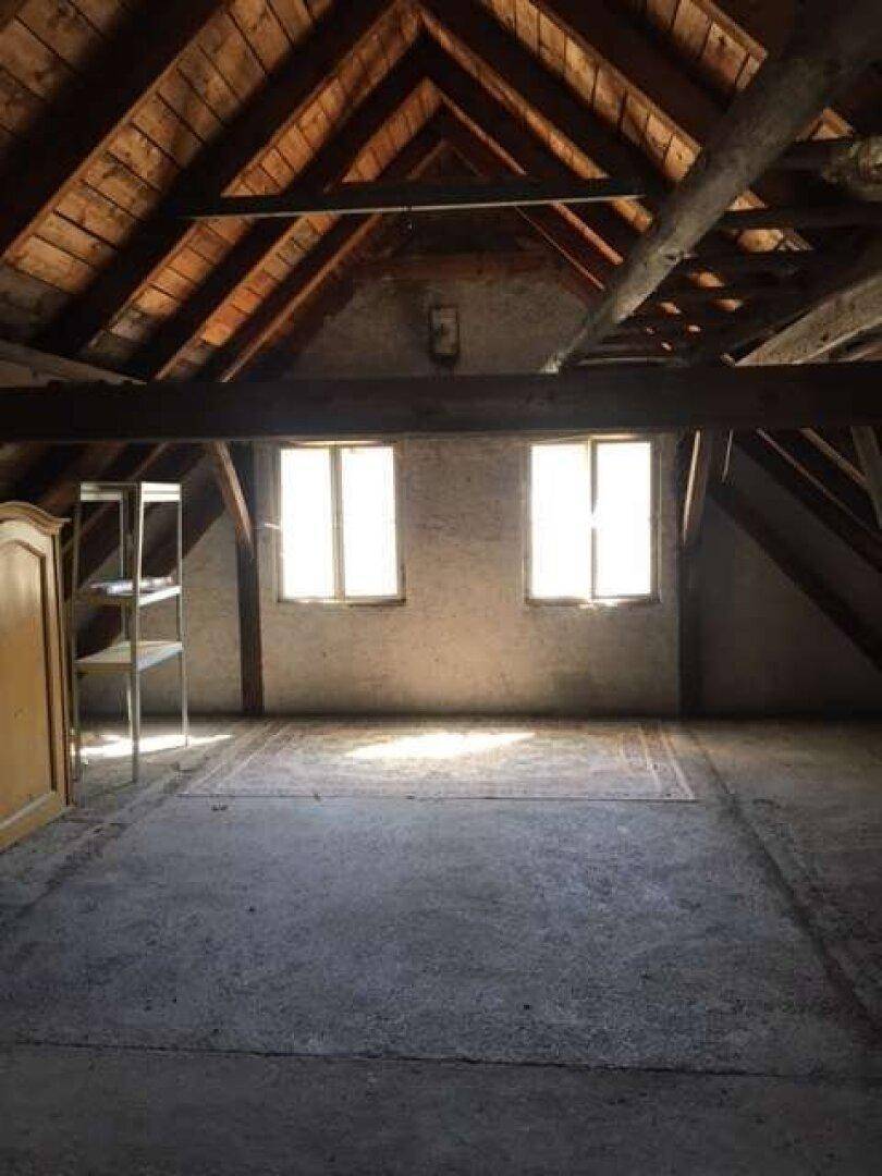 Geräumiger Dachboden mit sichtbaren Holzbalken, zwei Fenstern und viel Potenzial.