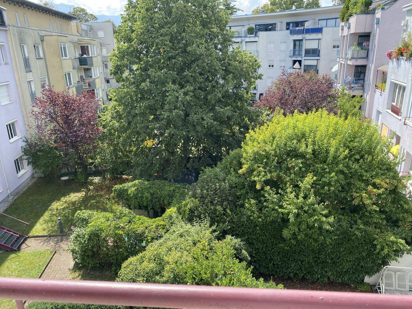 Balkon mit schöner Aussicht auf den grünen Innenhof und die umliegenden Gebäude.