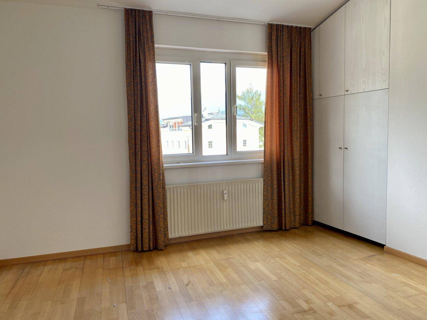 Schlafzimmer mit Holzparkett, großen Fenstern und praktischen Einbauschränken.