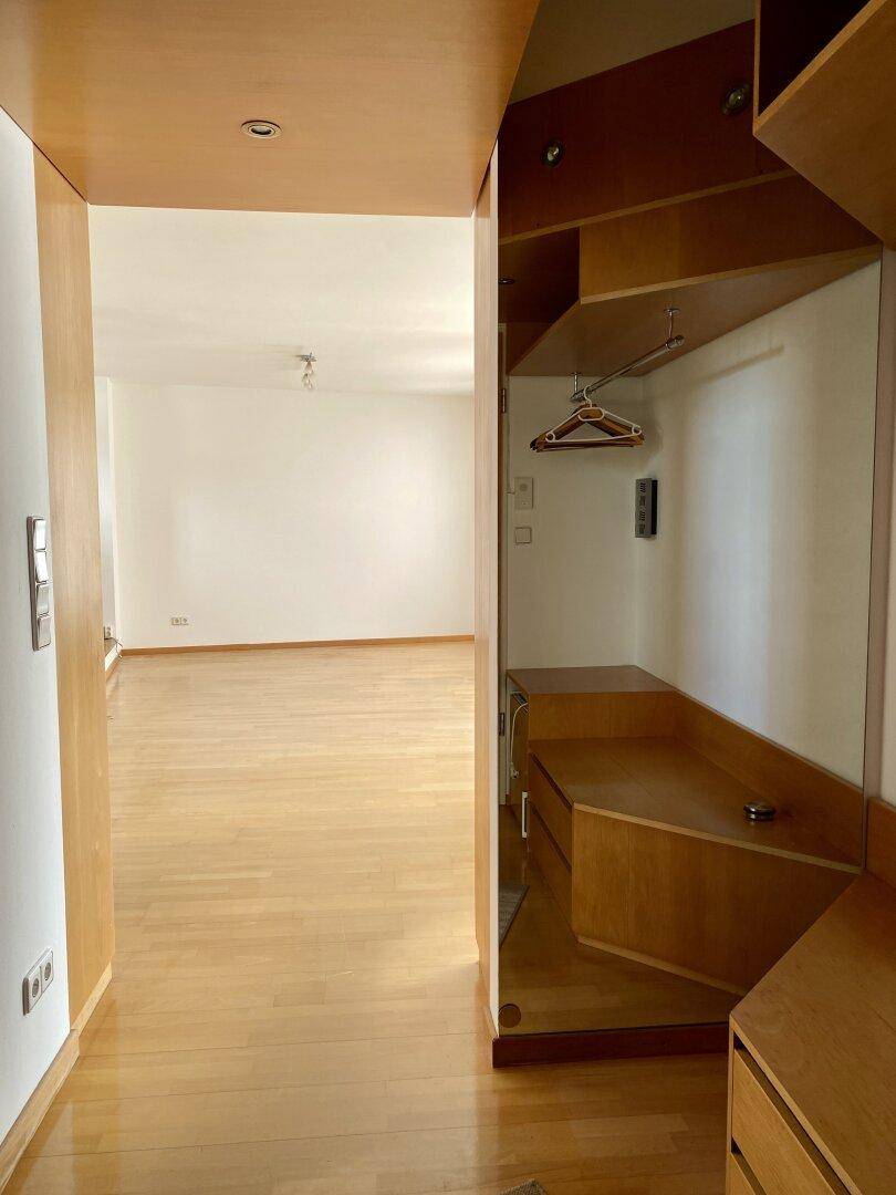 Eingangsbereich mit Holzparkett und praktischen Einbauschränken sowie Spiegel.