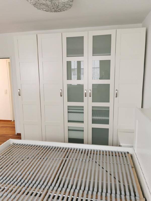 Schlafzimmer mit weißem Bett, Einbauschränken und Holzboden für eine gemütliche Atmosphäre.