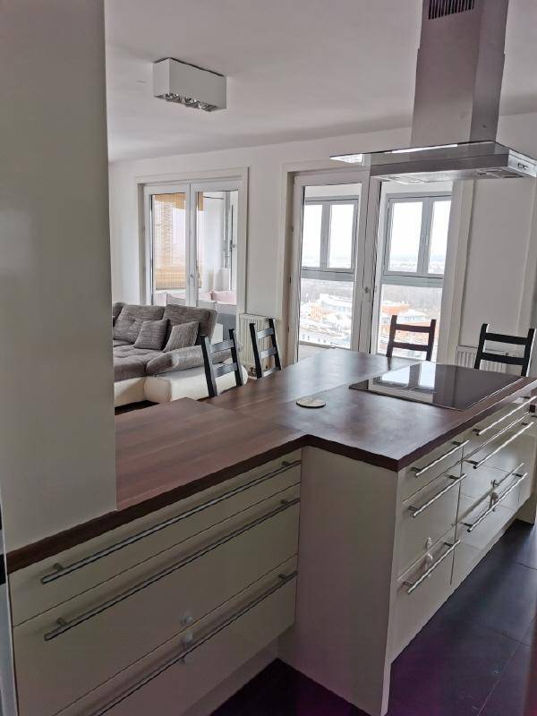 Moderne Küche mit Kochinsel und Blick in den hellen Wohnbereich mit großen Fenstern.