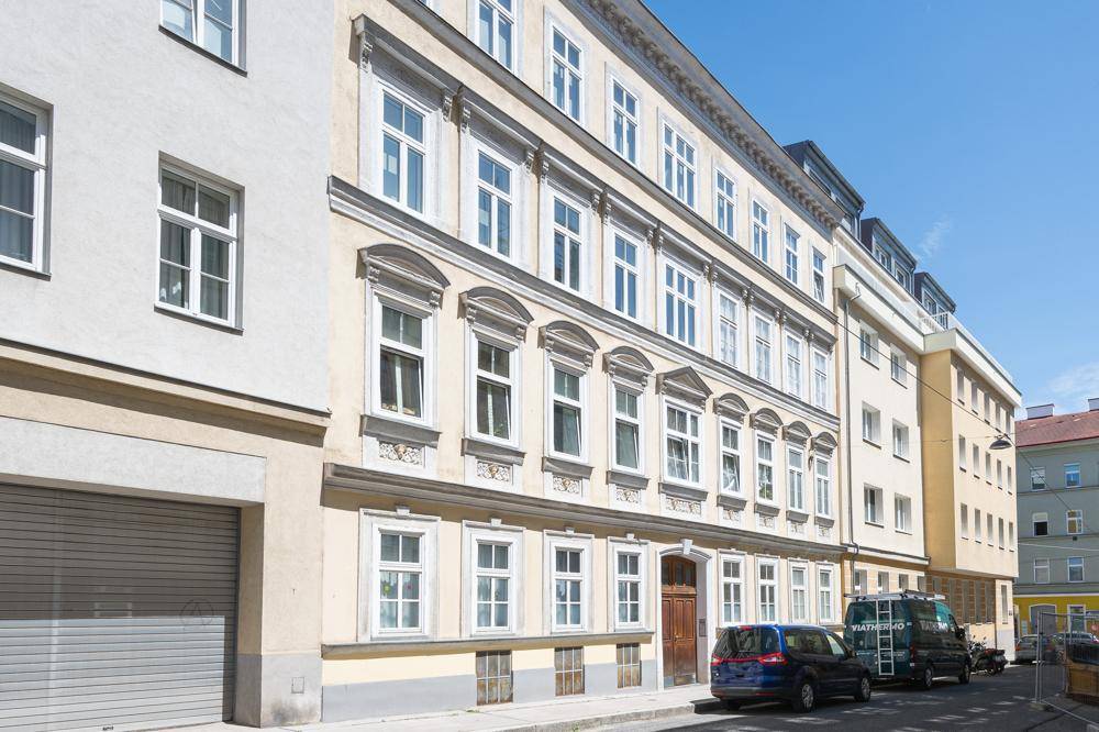 Klassische Fassade eines Altbaus mit vielen Fenstern und architektonischen Details.