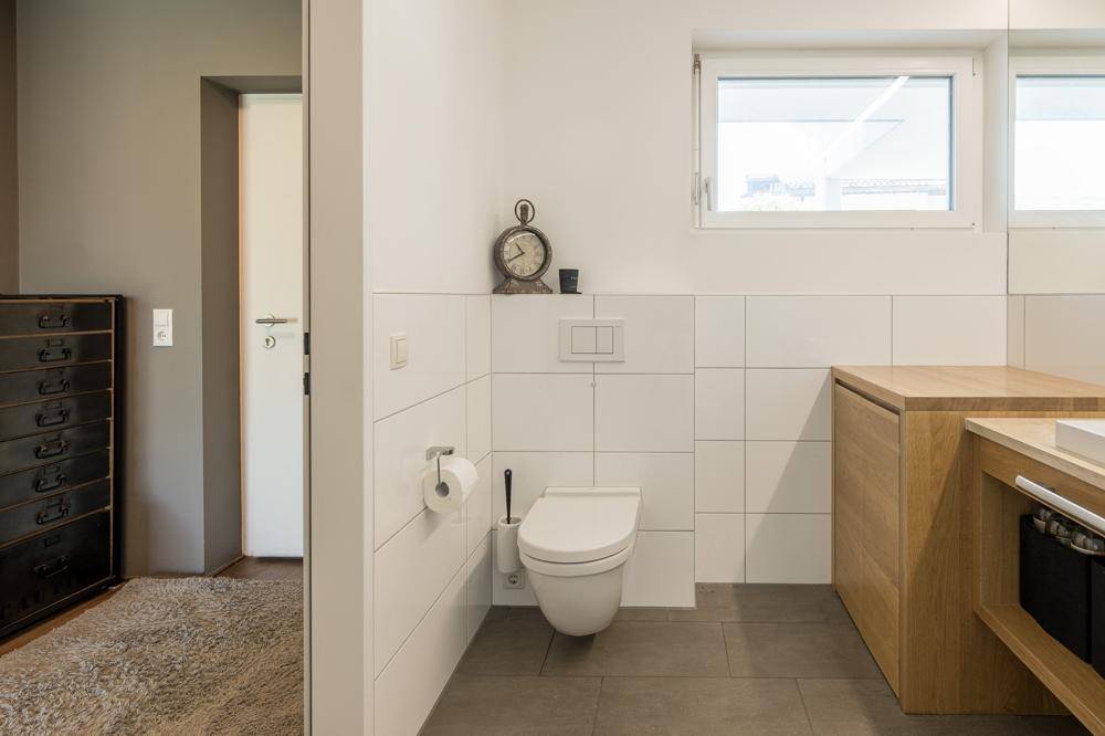Separater WC-Bereich im Badezimmer mit wandhängender Toilette und Fenster.
