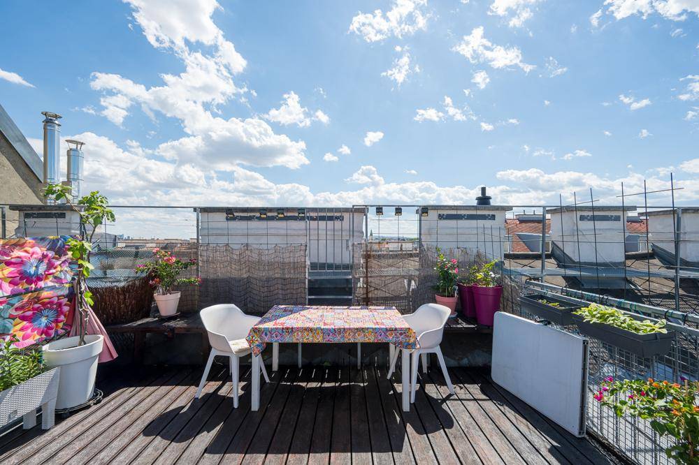 Geräumige Dachterrasse mit Holzdeck, Sitzgelegenheiten und weitem Blick über die Stadt.