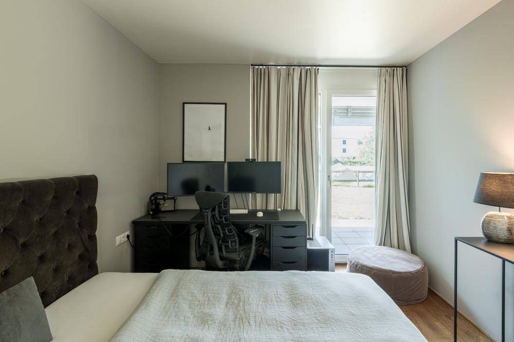 Schlafzimmer mit Doppelbett, Arbeitsbereich und direktem Zugang zu einem Außenbereich.