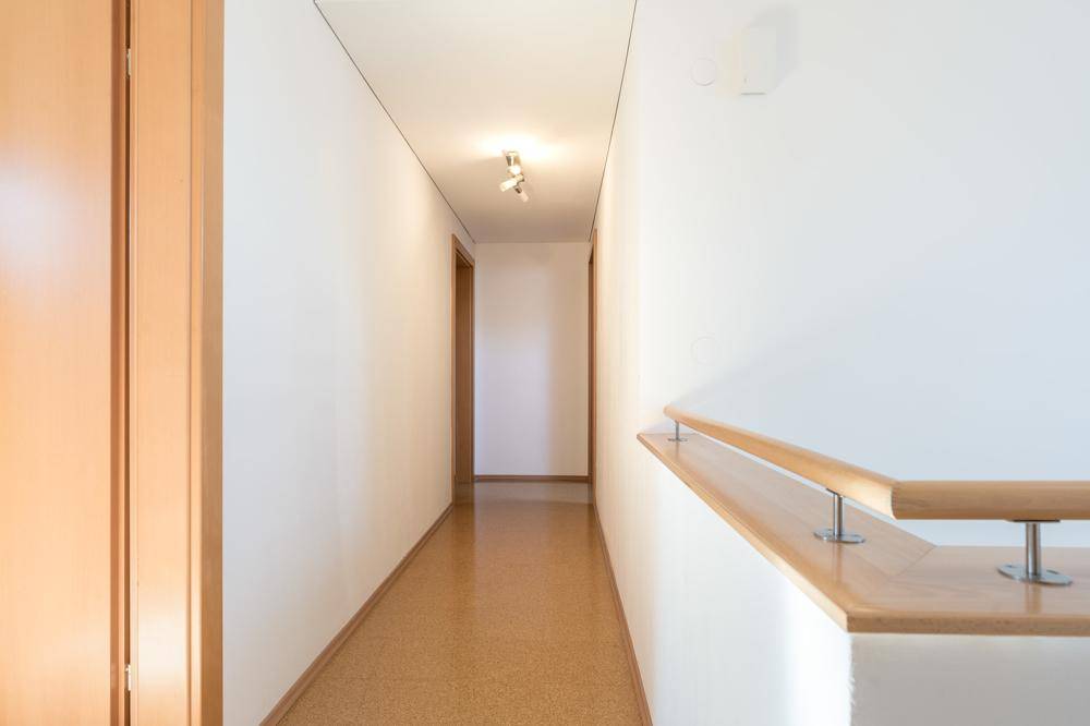 Langer, heller Flur mit Holzgeländer und schlichtem Design.