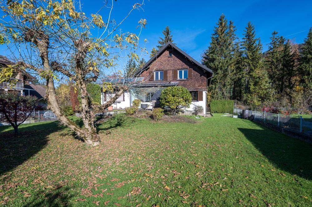 Freistehendes Haus mit gepflegtem Rasen und umgebender Natur unter blauem Himmel.