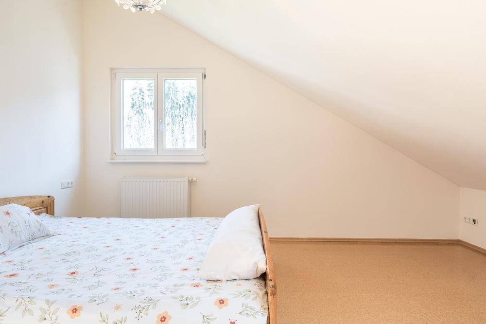 Helles Schlafzimmer im Dachgeschoss mit schrägen Wänden und Fenster.