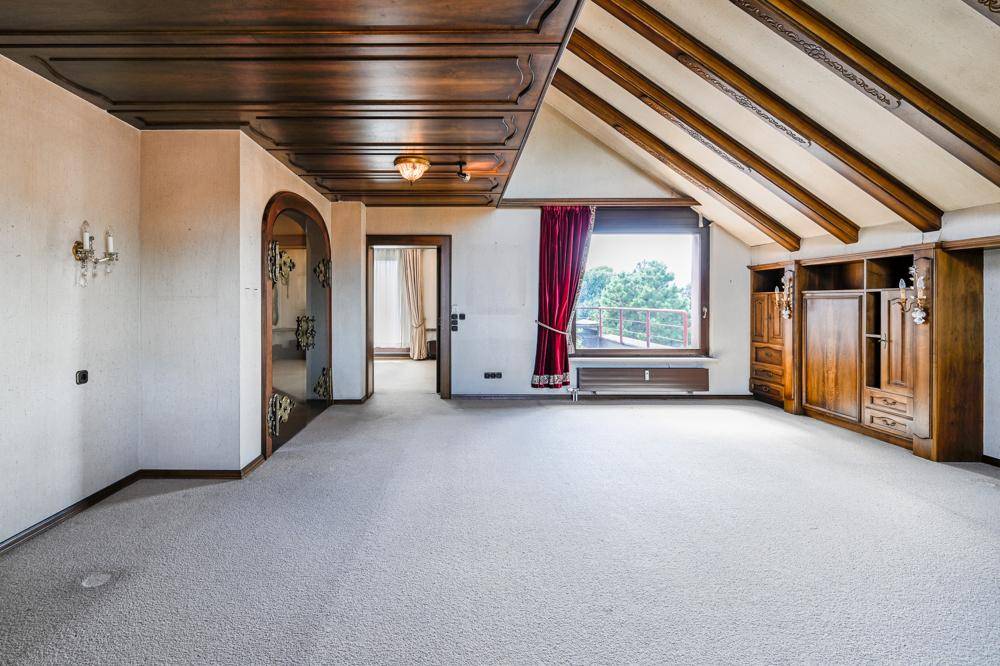 Geräumiges Zimmer mit Teppichboden, Holzbalkendecke und integrierten Holzschränken.